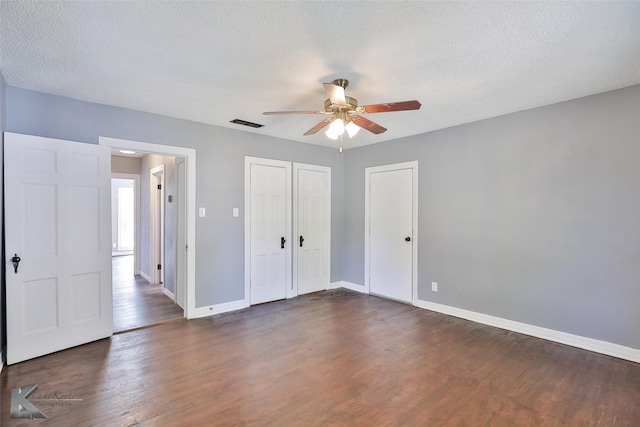 unfurnished bedroom featuring ceiling fan, dark hardwood / wood-style flooring, a closet, and a textured ceiling