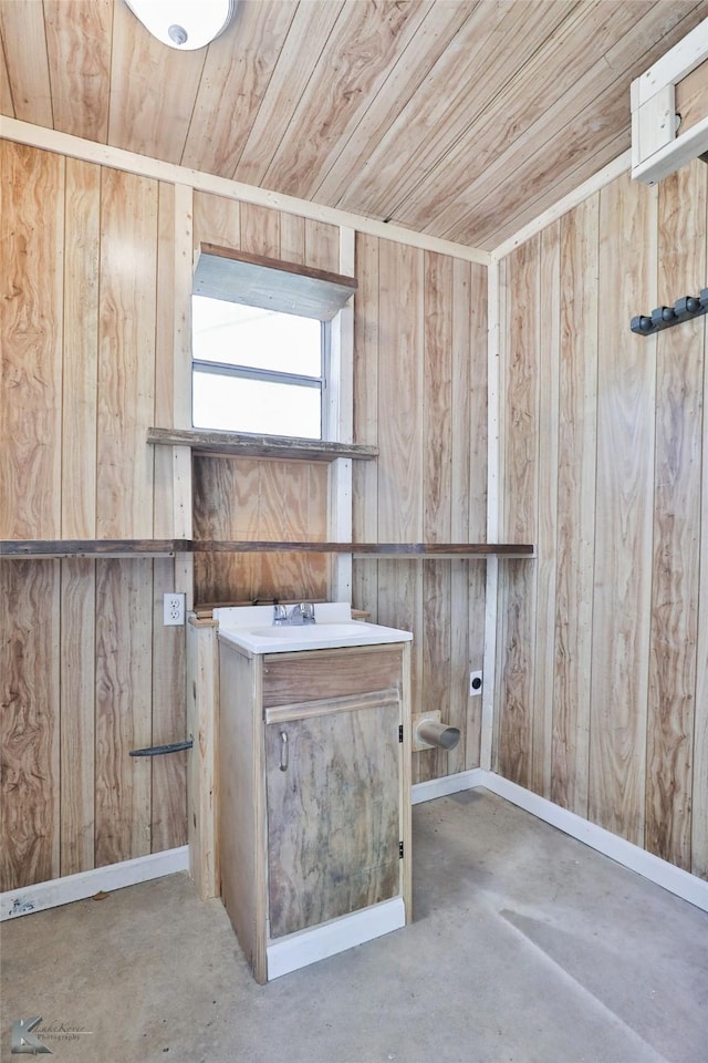 laundry area with wood ceiling, sink, and wood walls