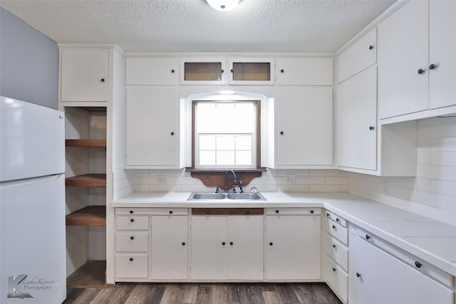 kitchen with sink, white cabinetry, white refrigerator, dark hardwood / wood-style flooring, and decorative backsplash