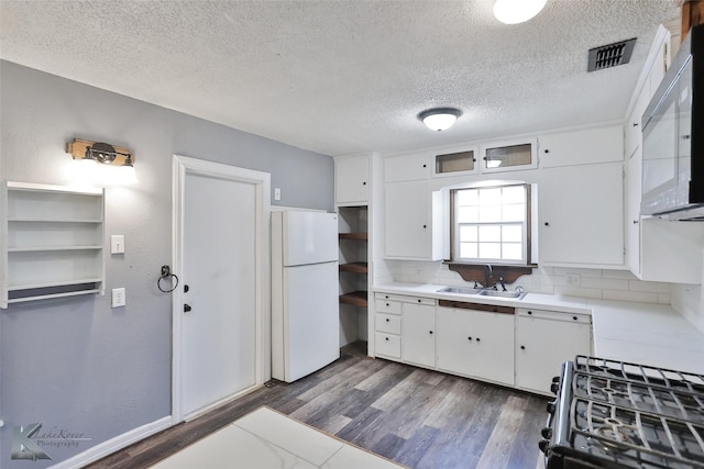 kitchen featuring sink, white cabinets, dark hardwood / wood-style flooring, white refrigerator, and gas stove