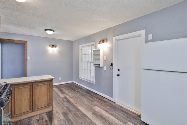 kitchen featuring white refrigerator, gas stove, a textured ceiling, dark hardwood / wood-style flooring, and tile countertops