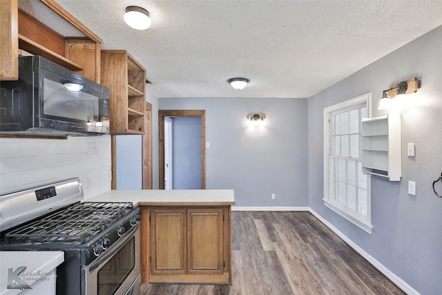 kitchen with dark wood-type flooring, kitchen peninsula, a textured ceiling, and stainless steel gas stove