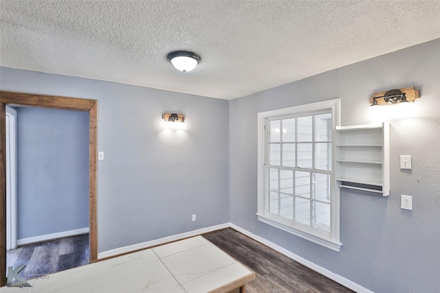 spare room featuring hardwood / wood-style flooring and a textured ceiling