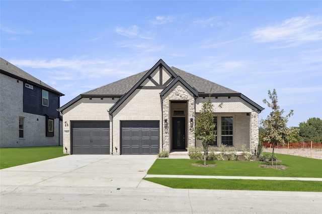 french provincial home featuring roof with shingles, brick siding, concrete driveway, a garage, and a front lawn
