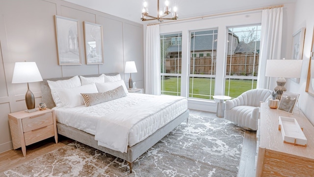 bedroom featuring a decorative wall, a chandelier, and wood finished floors
