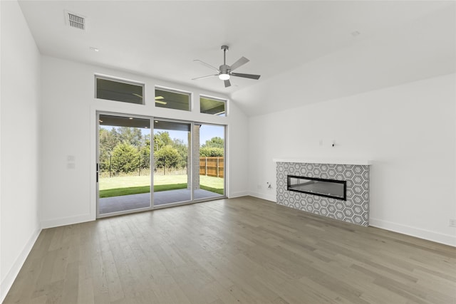 unfurnished living room with a tile fireplace, wood finished floors, visible vents, baseboards, and ceiling fan