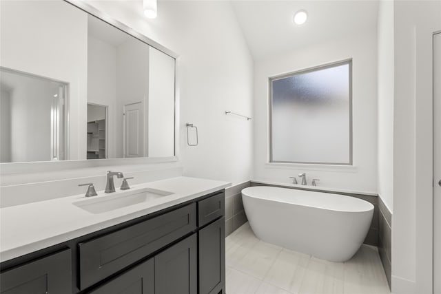 bathroom with vanity, lofted ceiling, and a freestanding tub