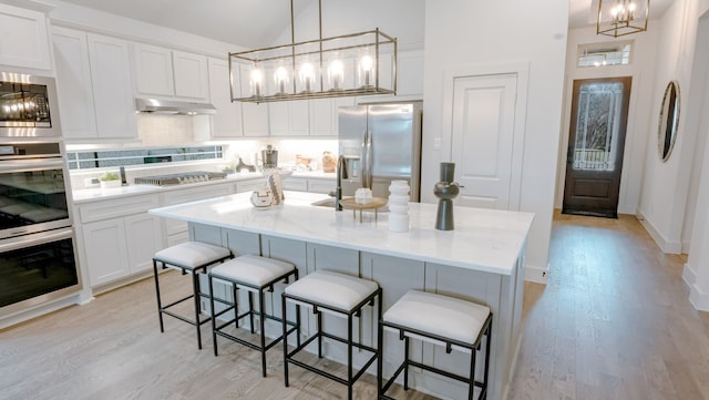 kitchen featuring white cabinetry, an inviting chandelier, appliances with stainless steel finishes, and under cabinet range hood