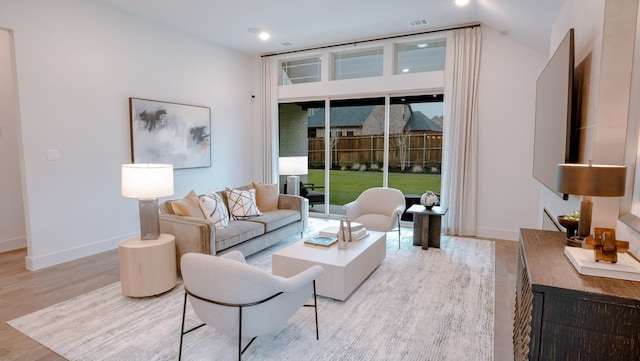 living room with light wood-type flooring, visible vents, and baseboards