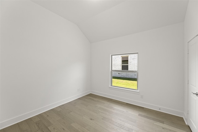 unfurnished bedroom featuring lofted ceiling, baseboards, and light wood-style flooring