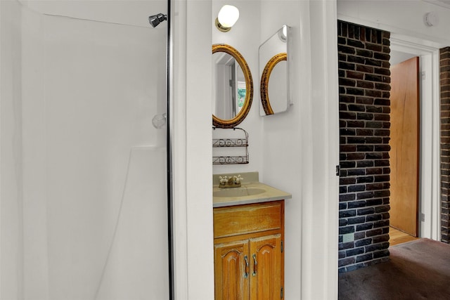 bathroom with vanity and brick wall