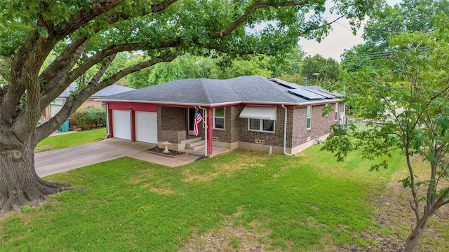 ranch-style house with solar panels, a garage, and a front yard