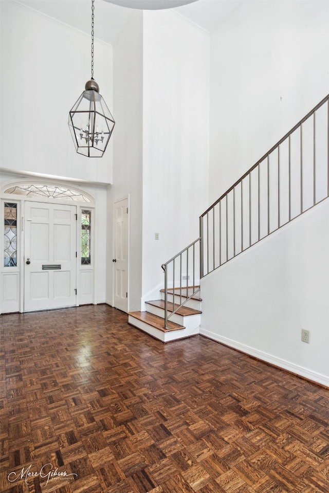 entryway featuring an inviting chandelier, dark parquet flooring, and a high ceiling