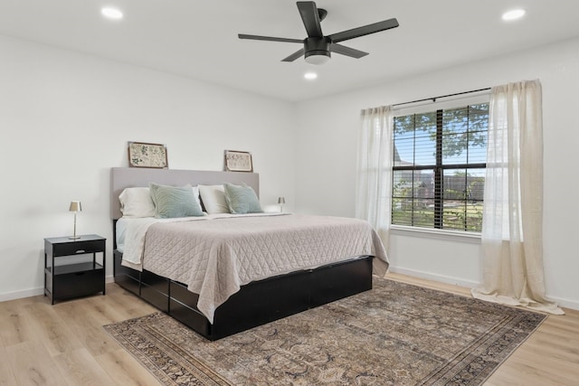 bedroom featuring ceiling fan, multiple windows, and light hardwood / wood-style floors