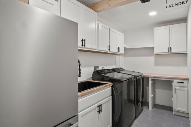 washroom featuring cabinets, dark tile patterned floors, sink, and independent washer and dryer