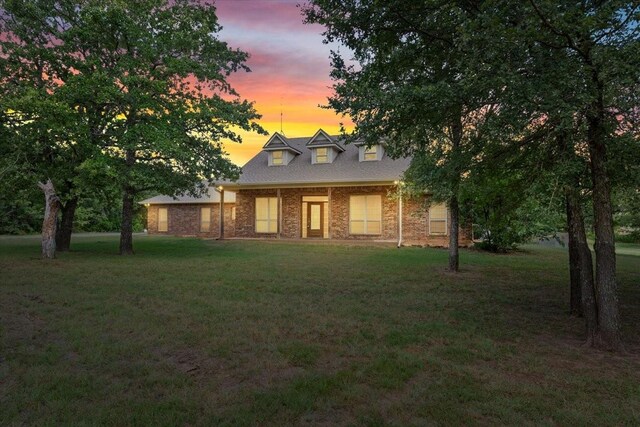 back house at dusk featuring a lawn