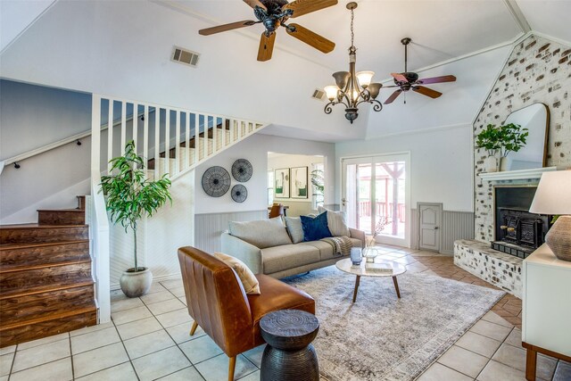 tiled living room featuring high vaulted ceiling, a tile fireplace, ceiling fan with notable chandelier, and ornamental molding