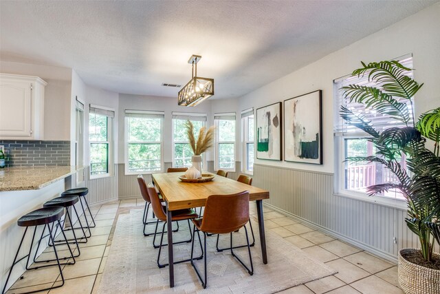 tiled dining area featuring an inviting chandelier and a textured ceiling