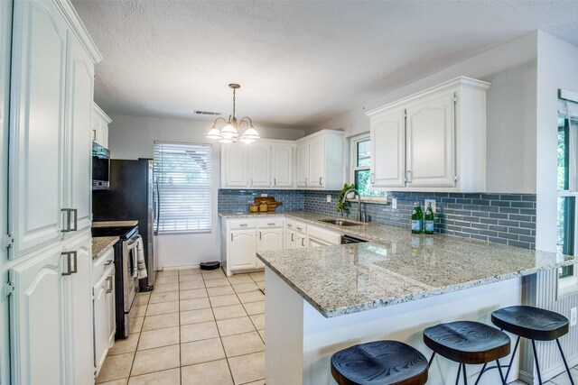 kitchen with stainless steel electric stove, white cabinets, sink, hanging light fixtures, and kitchen peninsula