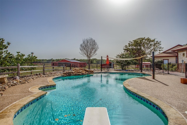 view of pool with a patio area and a diving board