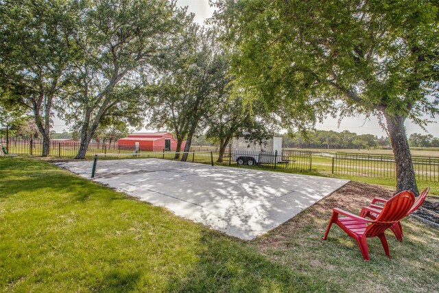 view of sport court with a lawn and a rural view