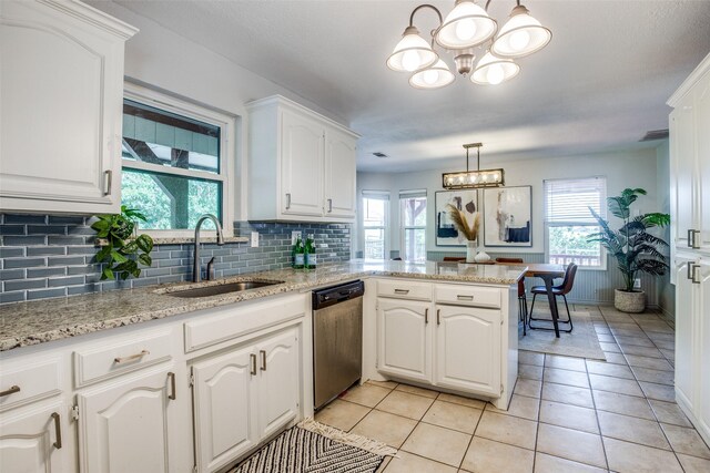 kitchen with pendant lighting, white cabinets, sink, kitchen peninsula, and stainless steel dishwasher