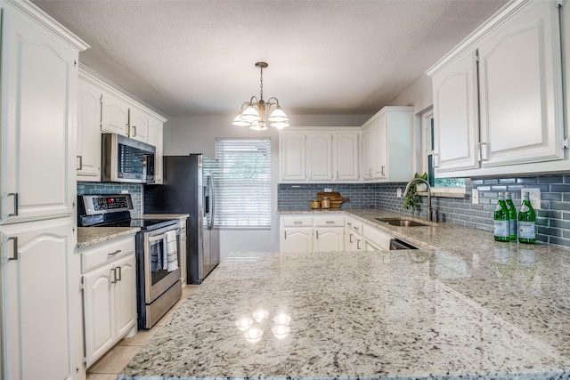 kitchen featuring pendant lighting, sink, an inviting chandelier, white cabinetry, and stainless steel appliances