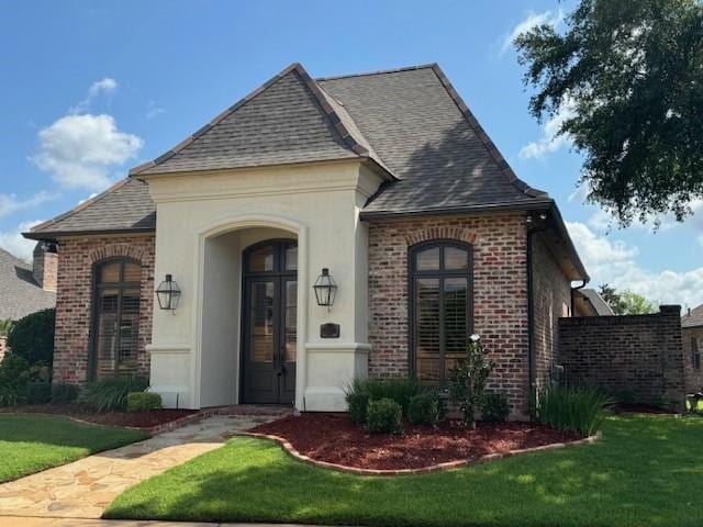 french country inspired facade featuring french doors and a front lawn