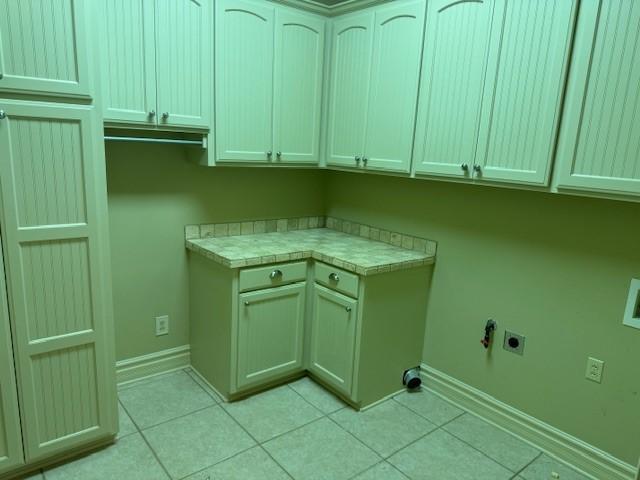 washroom featuring cabinets, electric dryer hookup, and light tile patterned floors