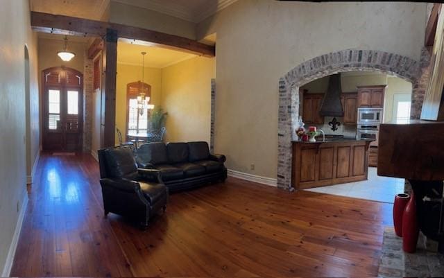 living room featuring ornamental molding, sink, a notable chandelier, and dark hardwood / wood-style flooring