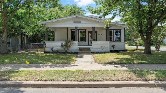 bungalow-style house featuring covered porch and a front yard