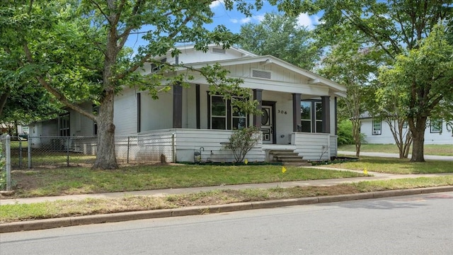 bungalow featuring a porch, a front yard, and fence