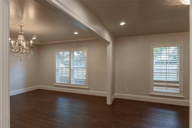 unfurnished room featuring a tray ceiling, dark hardwood / wood-style floors, and a notable chandelier