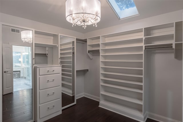 spacious closet featuring dark wood-type flooring, a skylight, and a chandelier