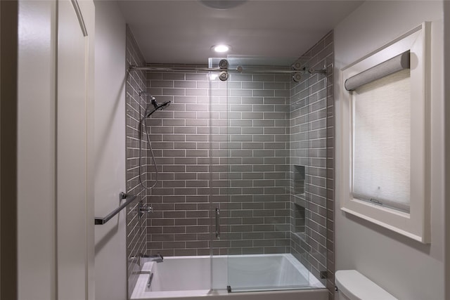 bathroom featuring plenty of natural light, combined bath / shower with glass door, and toilet