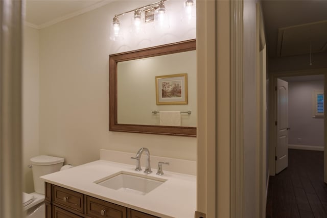 bathroom with toilet, vanity, wood-type flooring, and crown molding