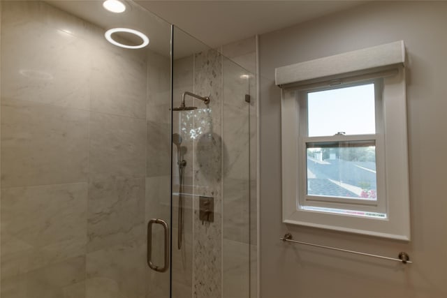 bathroom with a shower with shower door and a healthy amount of sunlight