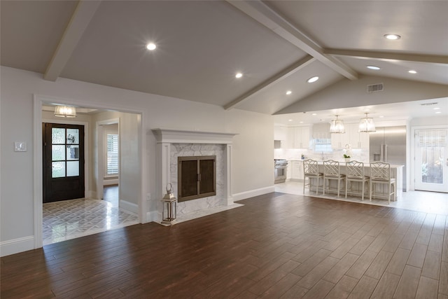 unfurnished living room with an inviting chandelier, lofted ceiling with beams, and a fireplace