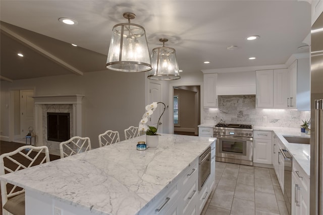 kitchen featuring a center island, white cabinetry, hanging light fixtures, appliances with stainless steel finishes, and a kitchen breakfast bar