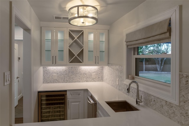 bar featuring sink, beverage cooler, and white cabinets