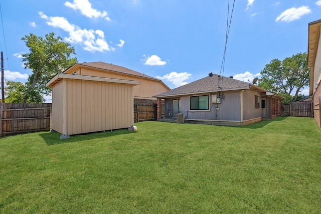 rear view of property featuring central air condition unit and a lawn