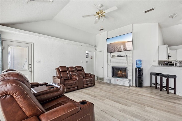 living room featuring a fireplace, ceiling fan, light hardwood / wood-style flooring, and a wealth of natural light