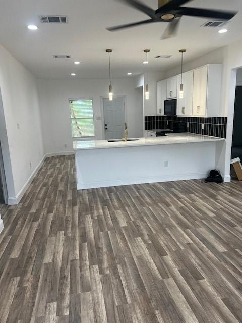 kitchen featuring decorative light fixtures, sink, white cabinets, dark hardwood / wood-style flooring, and kitchen peninsula