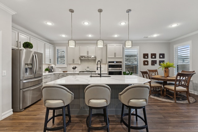 kitchen featuring a center island with sink, decorative light fixtures, dark hardwood / wood-style flooring, and appliances with stainless steel finishes