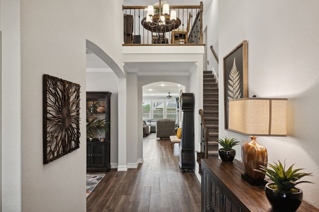 entrance foyer featuring dark hardwood / wood-style floors, crown molding, and an inviting chandelier