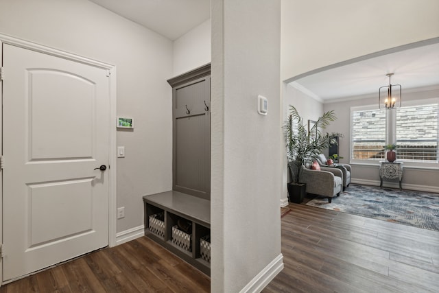 mudroom with a chandelier, crown molding, and dark wood-type flooring