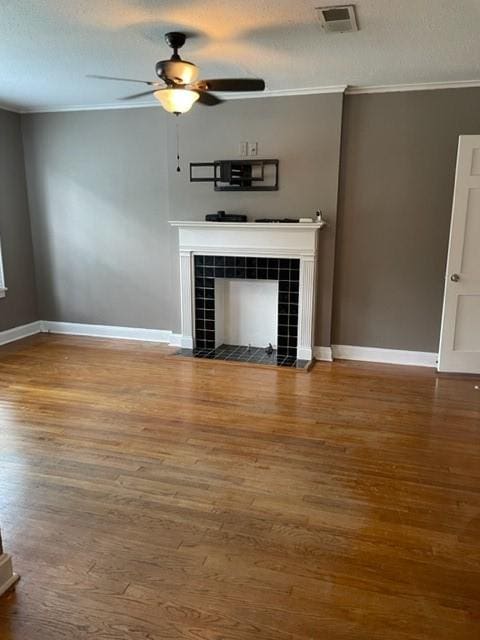 unfurnished living room featuring a fireplace, hardwood / wood-style flooring, ceiling fan, and ornamental molding