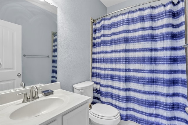 bathroom with walk in shower, vanity, and toilet