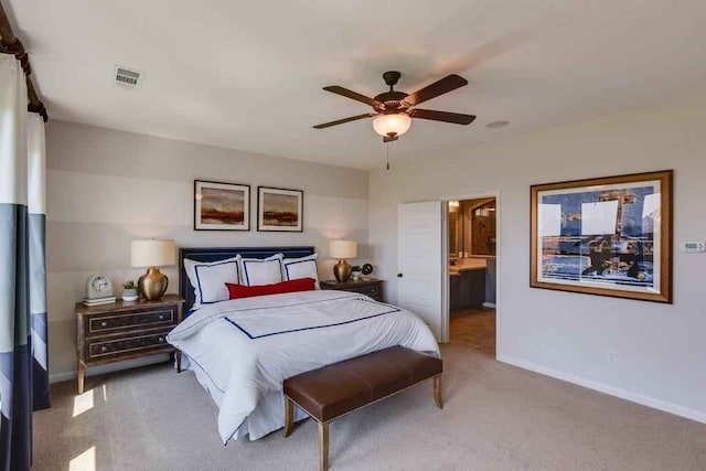 bedroom with ceiling fan, ensuite bathroom, and light carpet