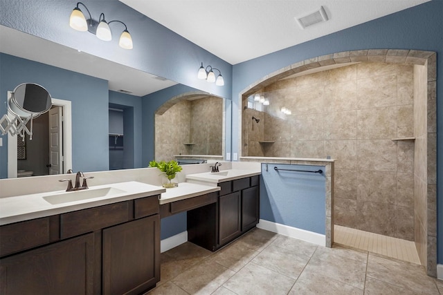 bathroom with a tile shower, tile patterned floors, and vanity